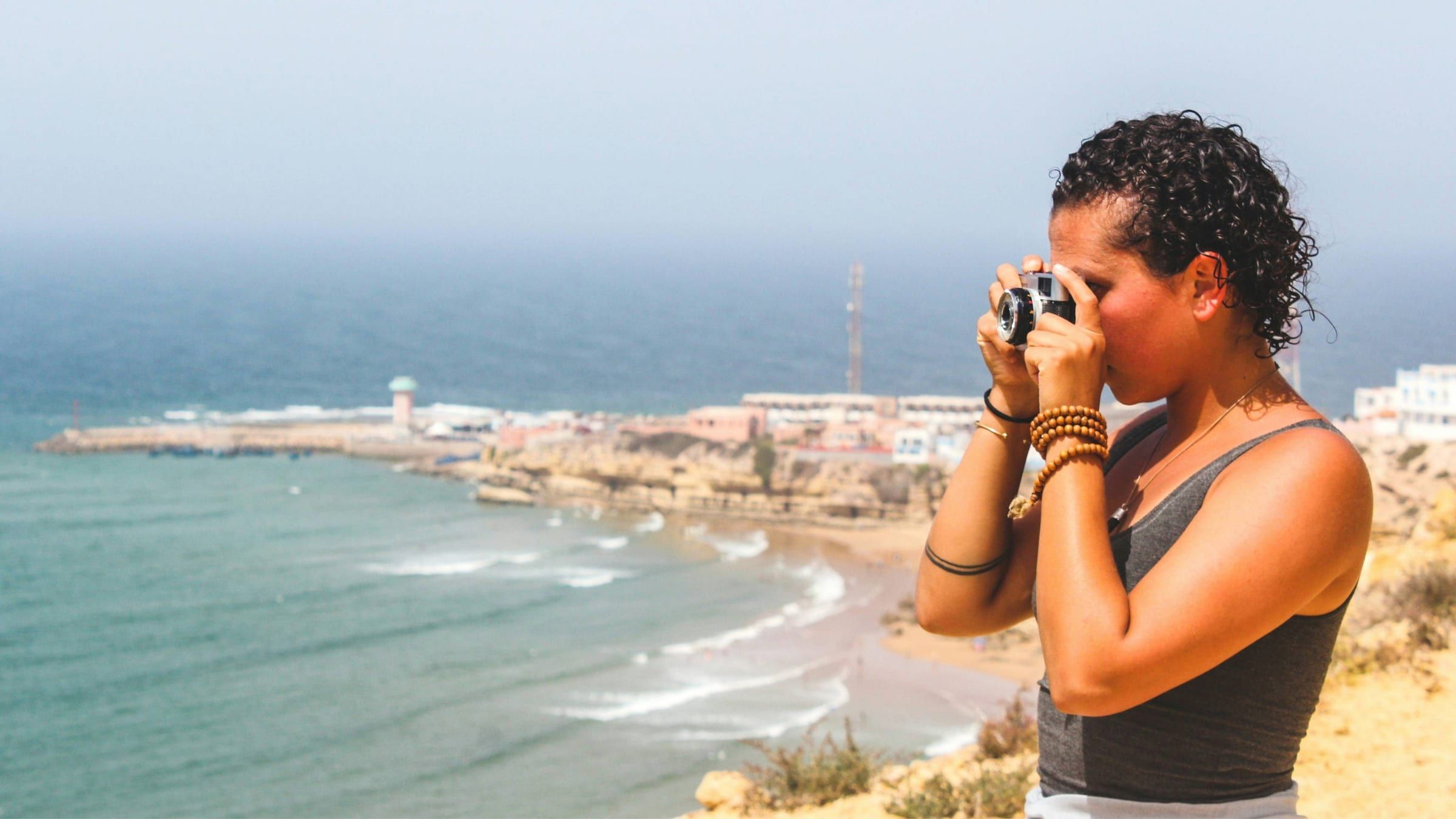 Traveller photographing the ocean from the cliffs of Imsouane