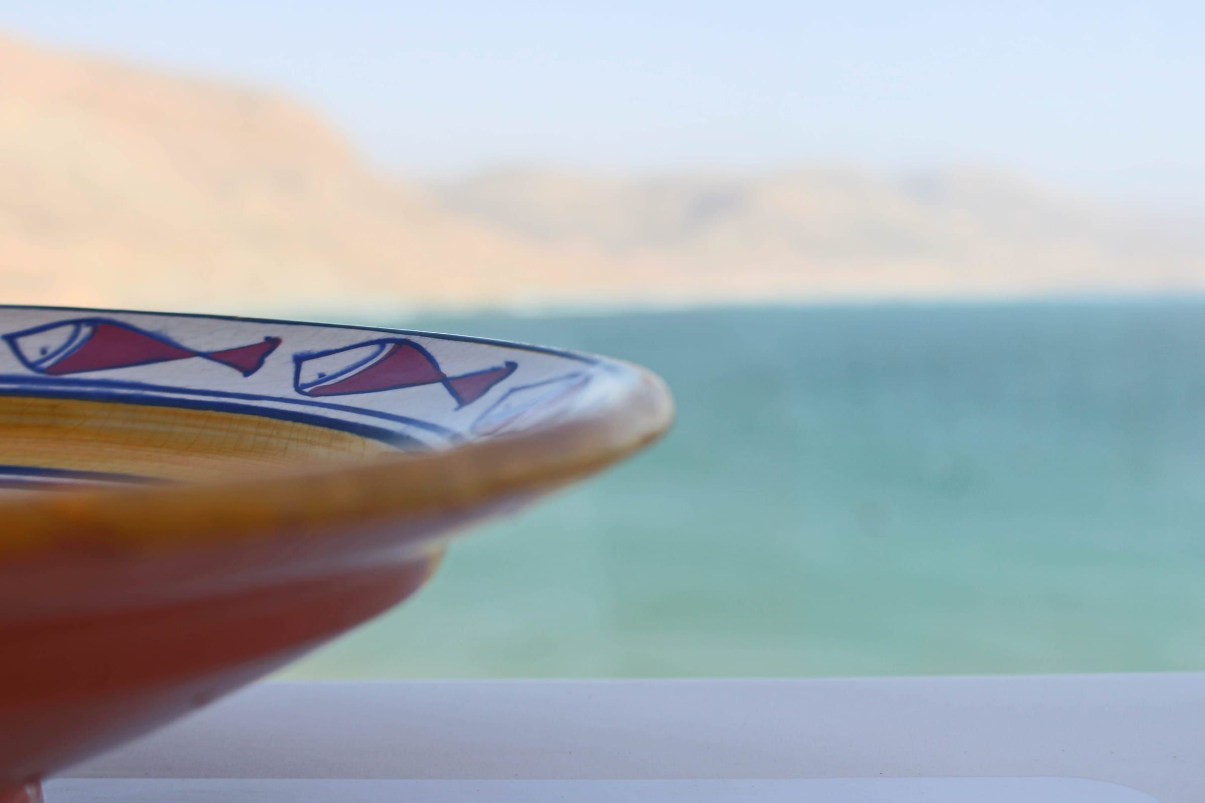 A painted Moroccan dish against the sea