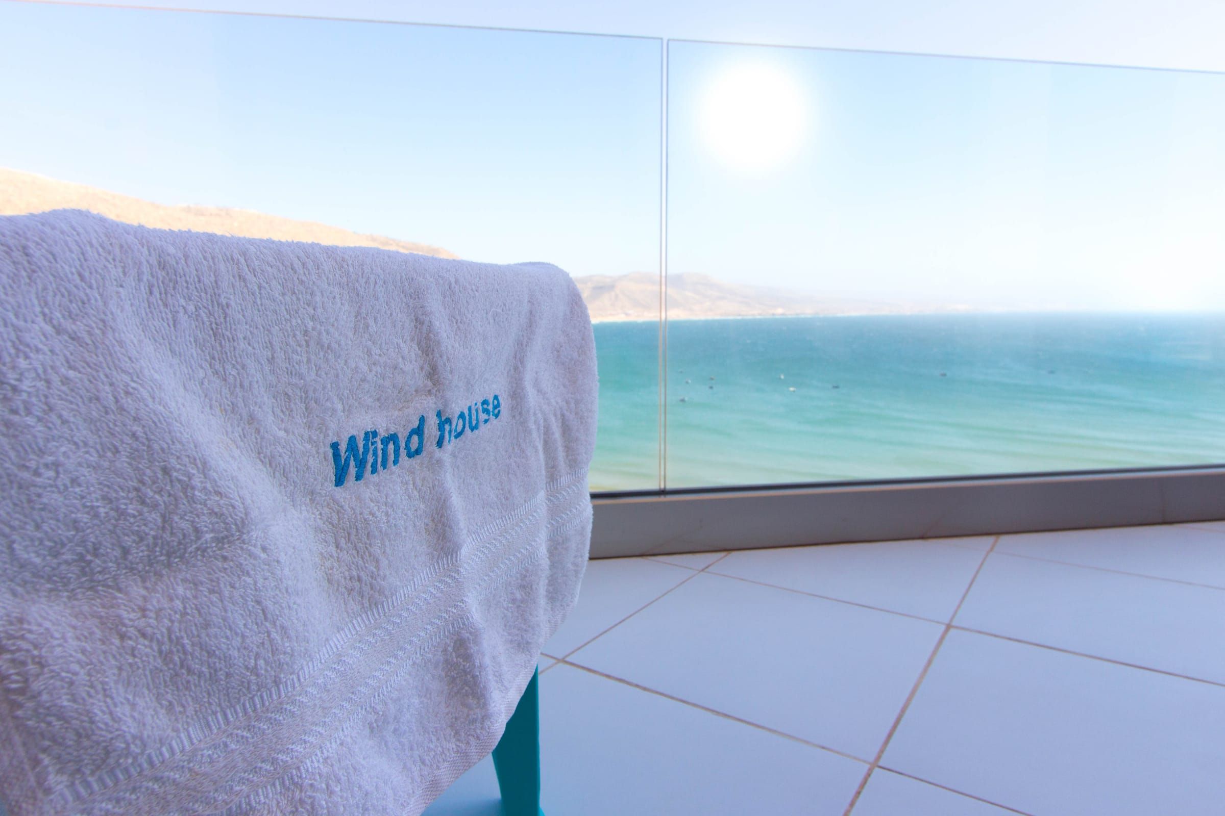 A Wind House towel on the balcony, the bay beyond the glass